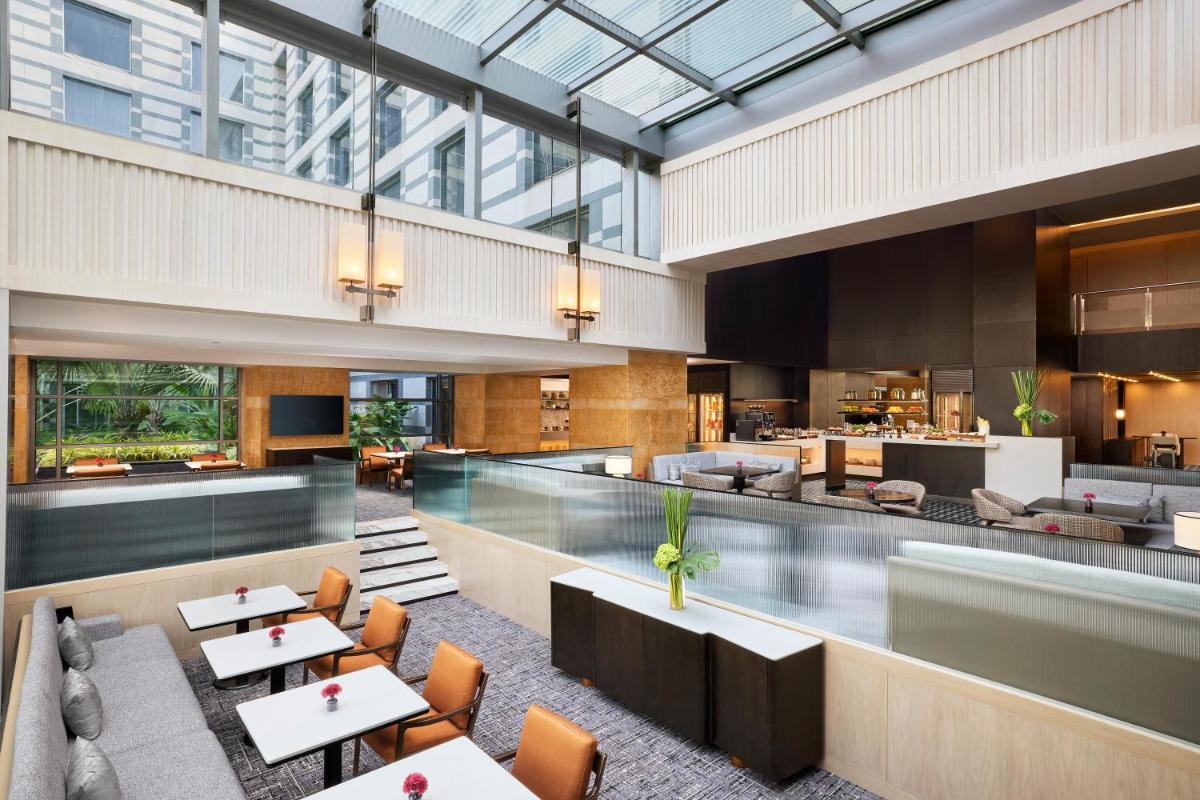 a lobby with tables and chairs and a restaurant at Grand Hyatt Mumbai Hotel and Residences in Mumbai