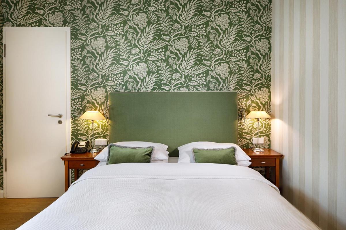 Schlafzimmer mit einem Bett mit einer grünen und weißen Tapete in der Unterkunft Hotel Goliath am Dom in Regensburg