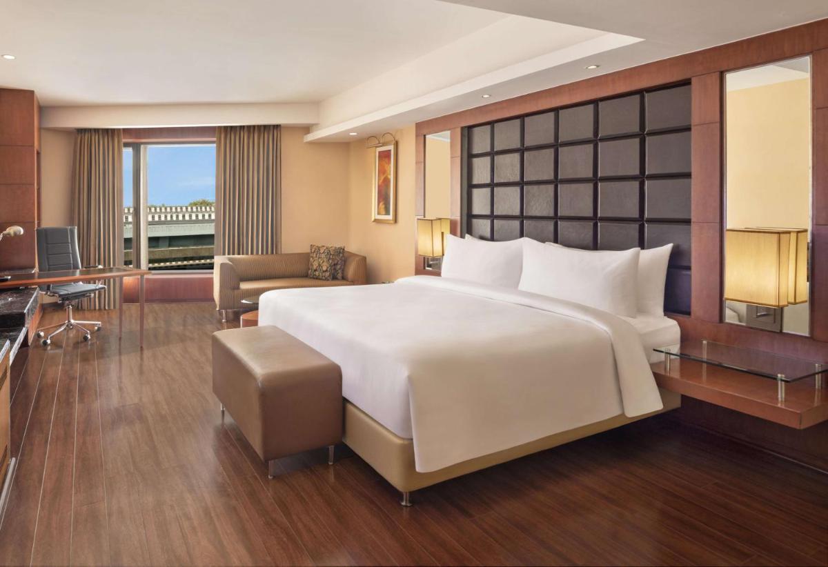 a hotel room with a large bed and a desk at Radisson Blu Plaza Delhi Airport in New Delhi a hotel room with a large bed and a desk at Radisson Blu Plaza Delhi Airport in New Delhi