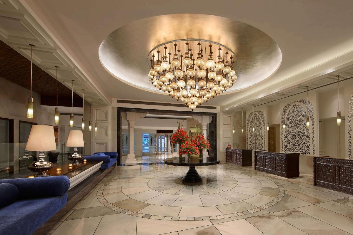 a lobby with a large chandelier and a blue couch at ITC Mughal, A Luxury Collection Resort & Spa, Agra in Agra