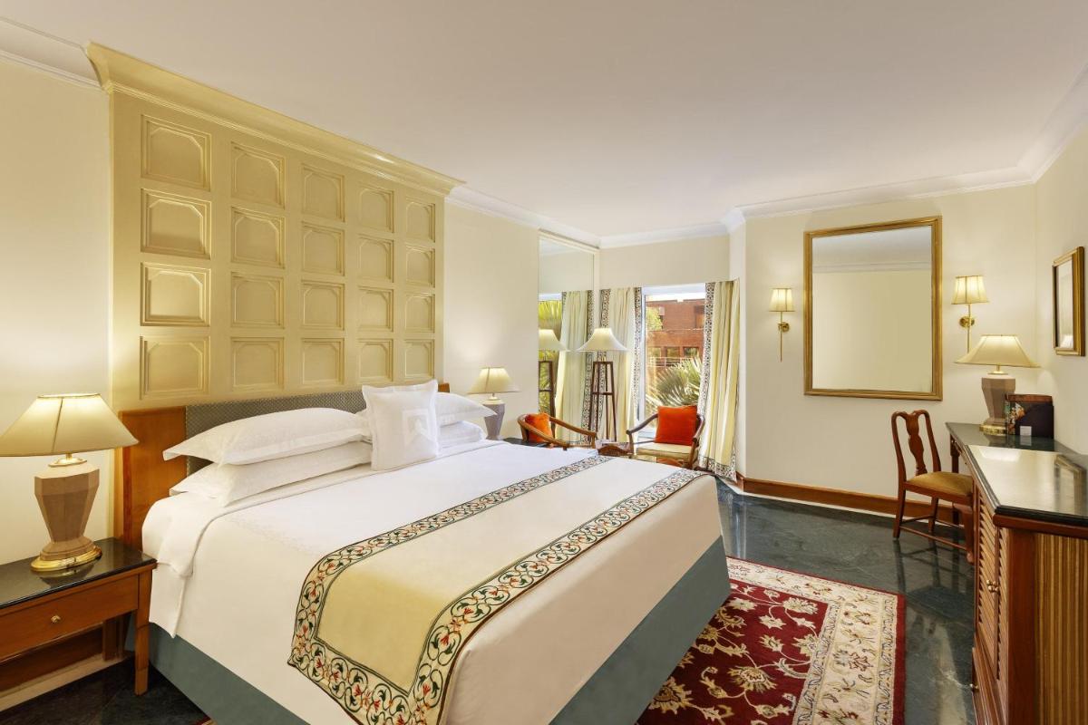 a bedroom with a large white bed and a desk at ITC Mughal, A Luxury Collection Resort & Spa, Agra in Agra +32 photos