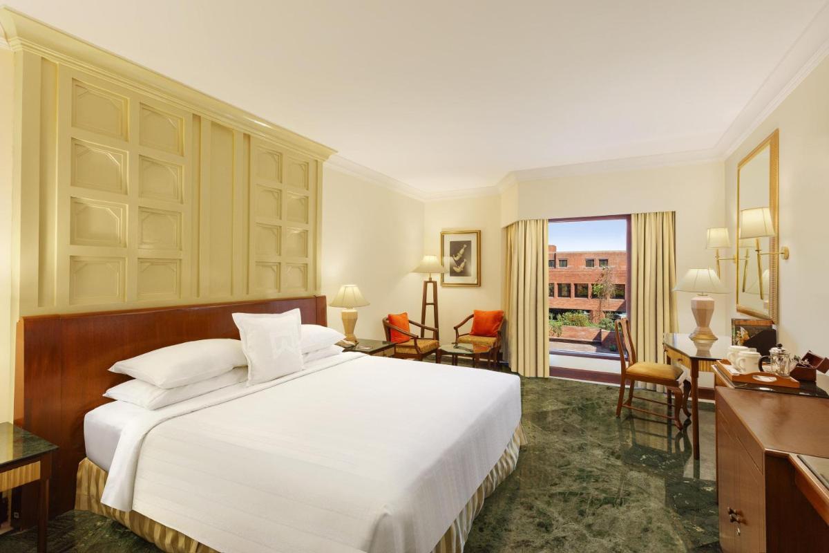 a bedroom with a large white bed and a desk at ITC Mughal, A Luxury Collection Resort & Spa, Agra in Agra