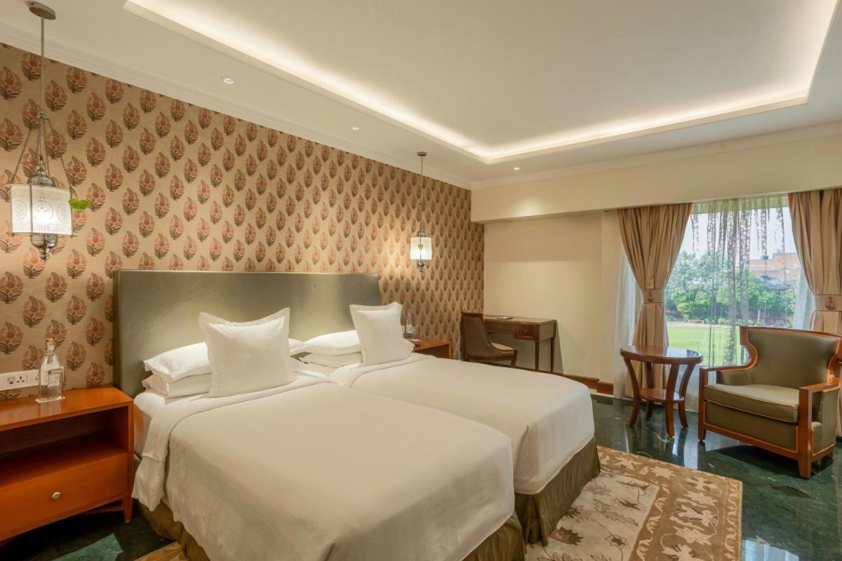 a hotel room with a large bed and a chair at ITC Mughal, A Luxury Collection Resort & Spa, Agra in Agra