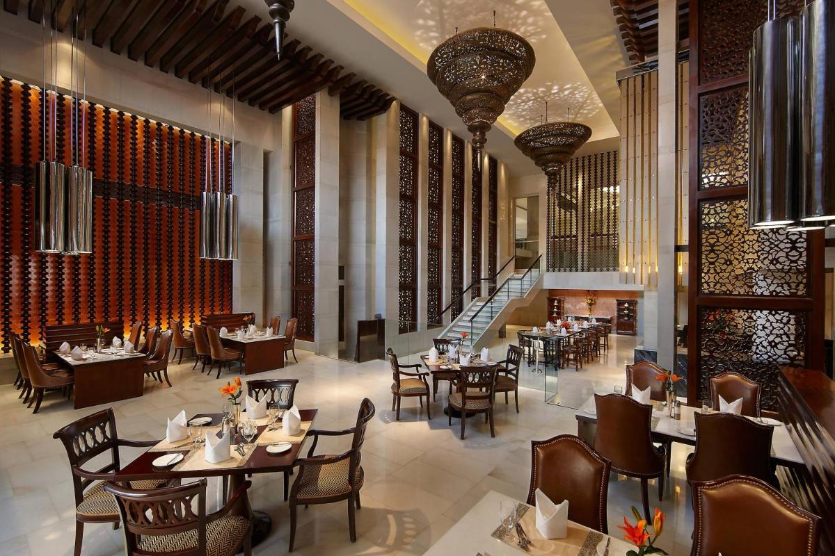 a restaurant with tables and chairs and a staircase at ITC Mughal, A Luxury Collection Resort & Spa, Agra in Agra