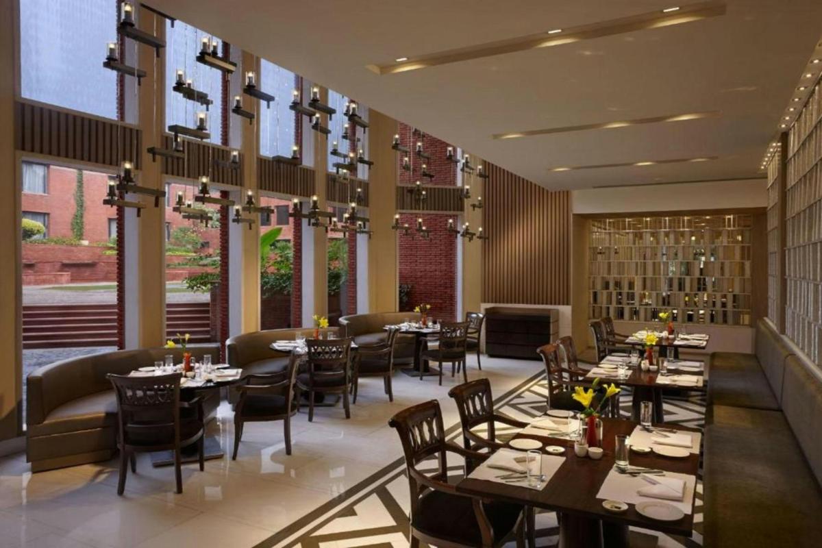 a dining room with tables and chairs and windows at ITC Mughal, A Luxury Collection Resort & Spa, Agra in Agra