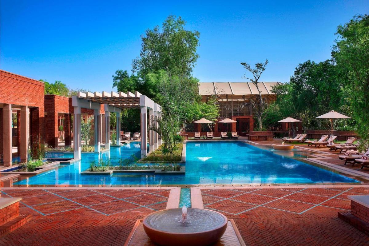 a large swimming pool with chairs and umbrellas at ITC Mughal, A Luxury Collection Resort & Spa, Agra in Agra