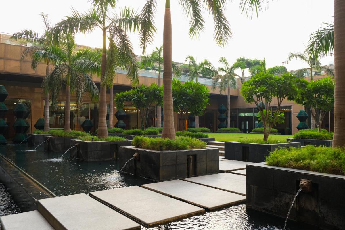 a building with palm trees and a pond in front of it at Crowne Plaza Today Gurugram by IHG in Gurgaon