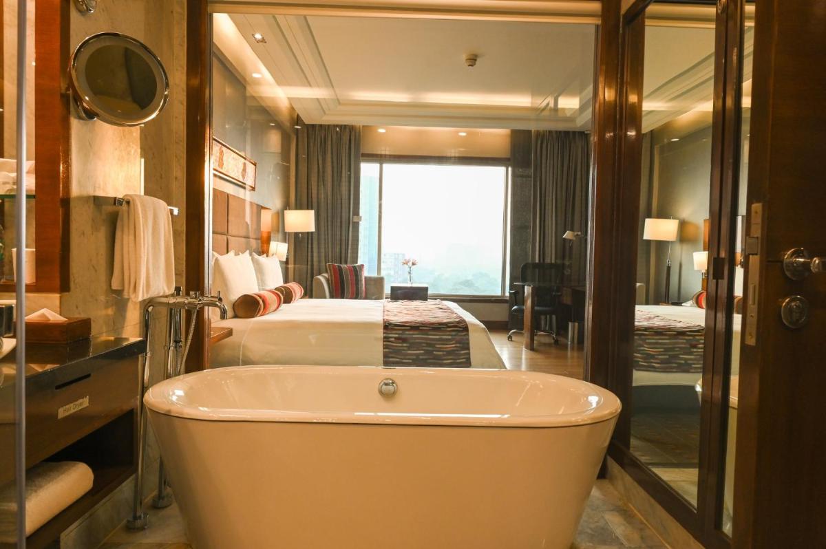 a bathroom with a bath tub and a bedroom at Crowne Plaza Today Gurugram by IHG in Gurgaon
