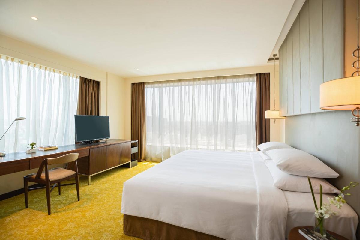 a hotel room with a bed and a desk and a television at Renaissance Ahmedabad Hotel in Ahmedabad