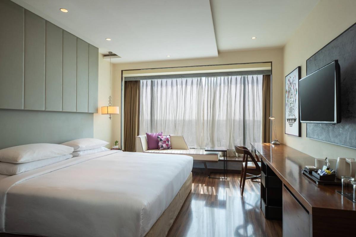 a bedroom with a large bed and a living room at Renaissance Ahmedabad Hotel in Ahmedabad