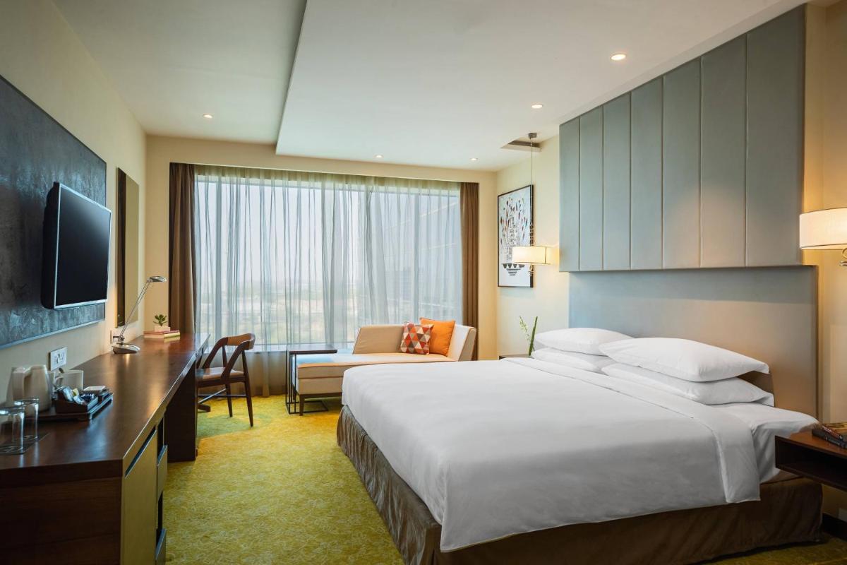 a hotel room with a large bed and a desk at Renaissance Ahmedabad Hotel in Ahmedabad