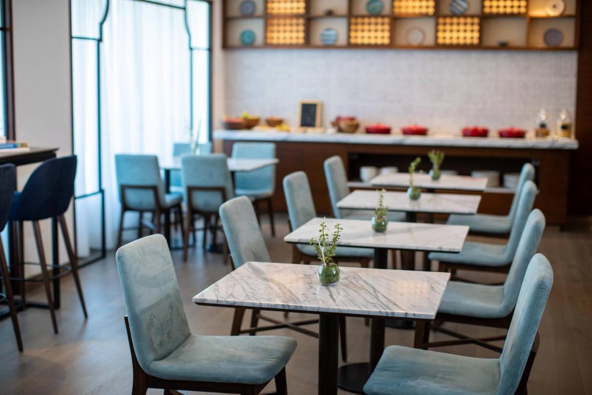 a restaurant with tables and chairs and a counter at Renaissance Ahmedabad Hotel in Ahmedabad