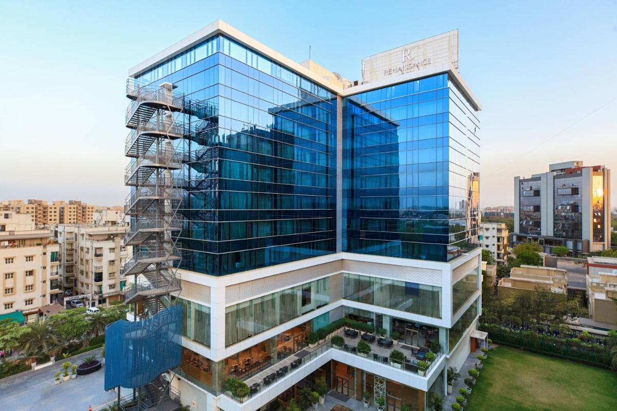 a tall glass building in a city at Renaissance Ahmedabad Hotel in Ahmedabad