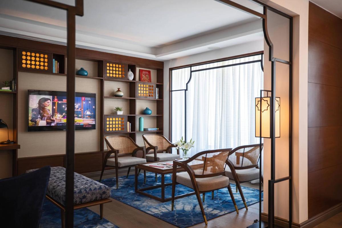 a living room with chairs and a table and a tv at Renaissance Ahmedabad Hotel in Ahmedabad