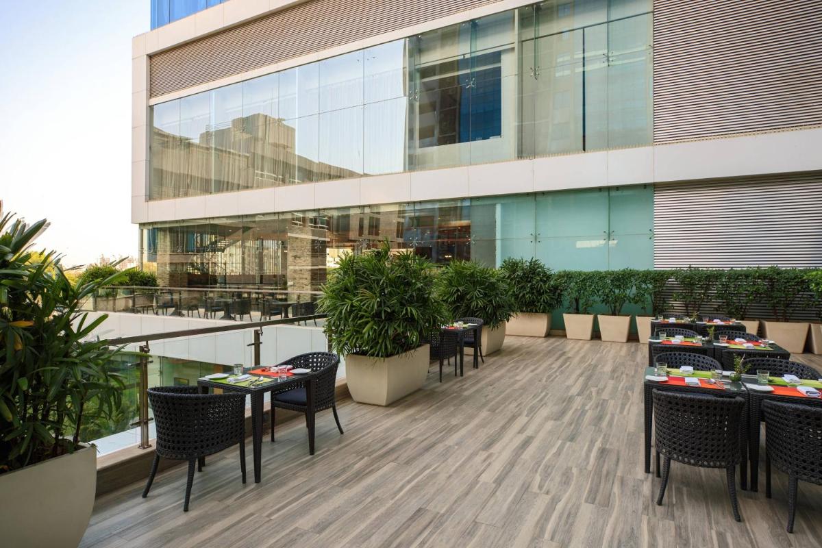 a balcony with tables and chairs and a building at Renaissance Ahmedabad Hotel in Ahmedabad