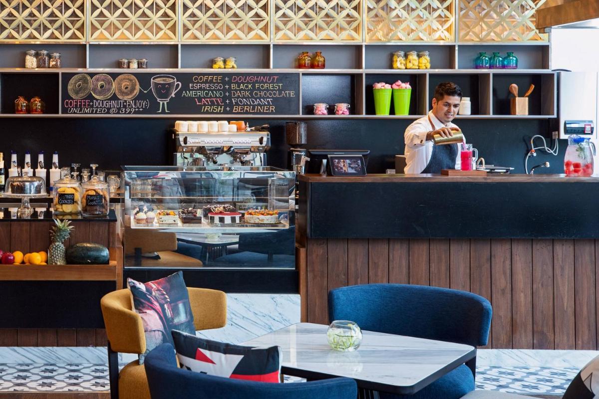 a man standing behind the counter of a restaurant at Renaissance Ahmedabad Hotel in Ahmedabad