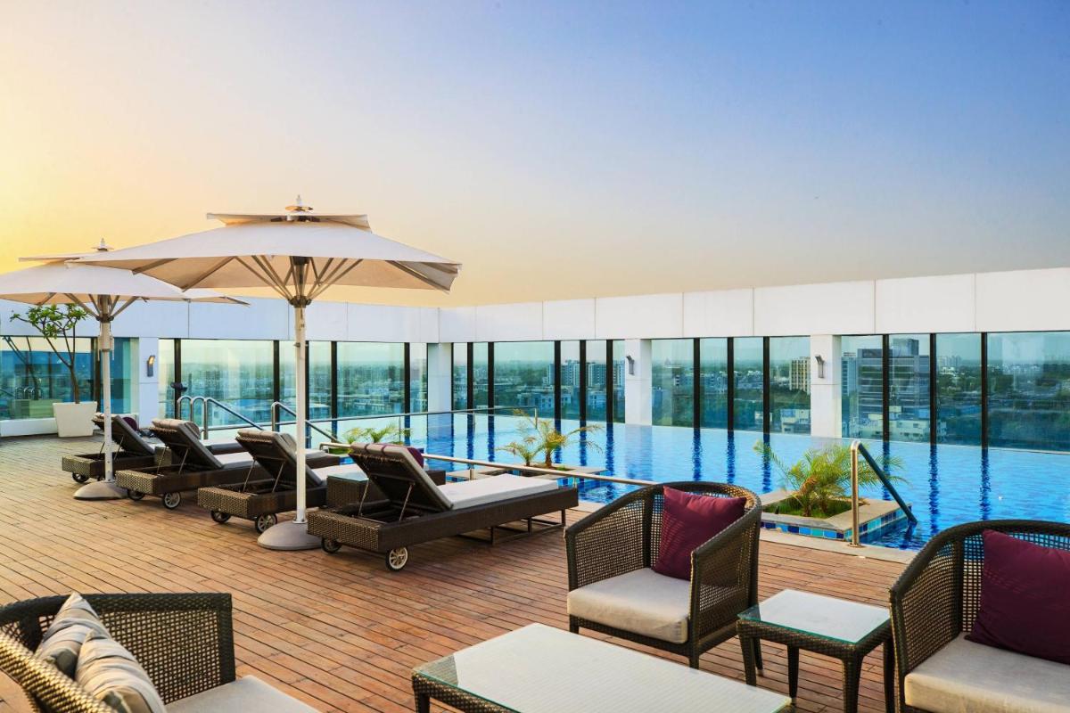 a large swimming pool with chairs and an umbrella at Renaissance Ahmedabad Hotel in Ahmedabad