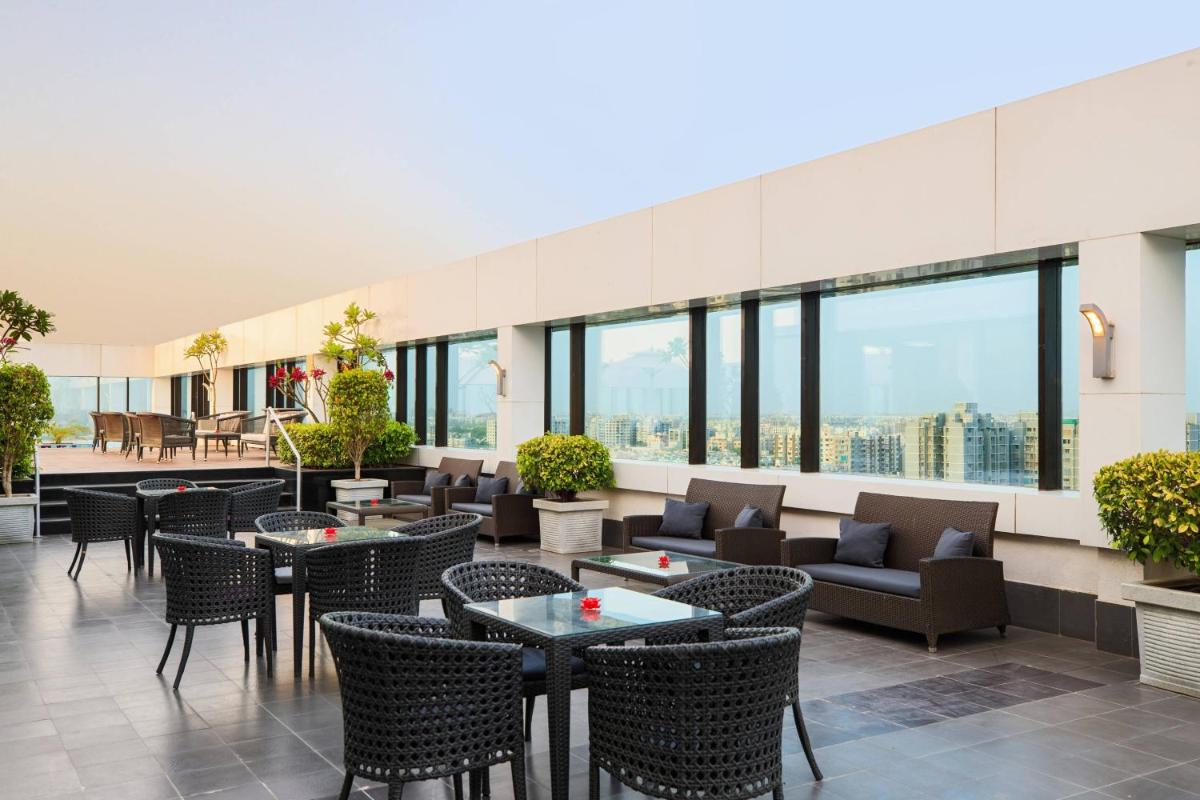 a hotel lobby with tables and chairs and windows at Renaissance Ahmedabad Hotel in Ahmedabad