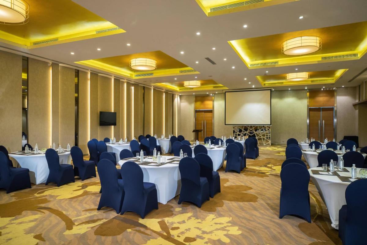 a conference room with tables and chairs and a screen at Renaissance Ahmedabad Hotel in Ahmedabad