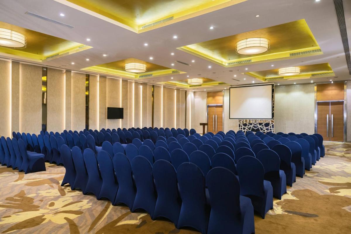 a conference room with blue chairs and a screen at Renaissance Ahmedabad Hotel in Ahmedabad