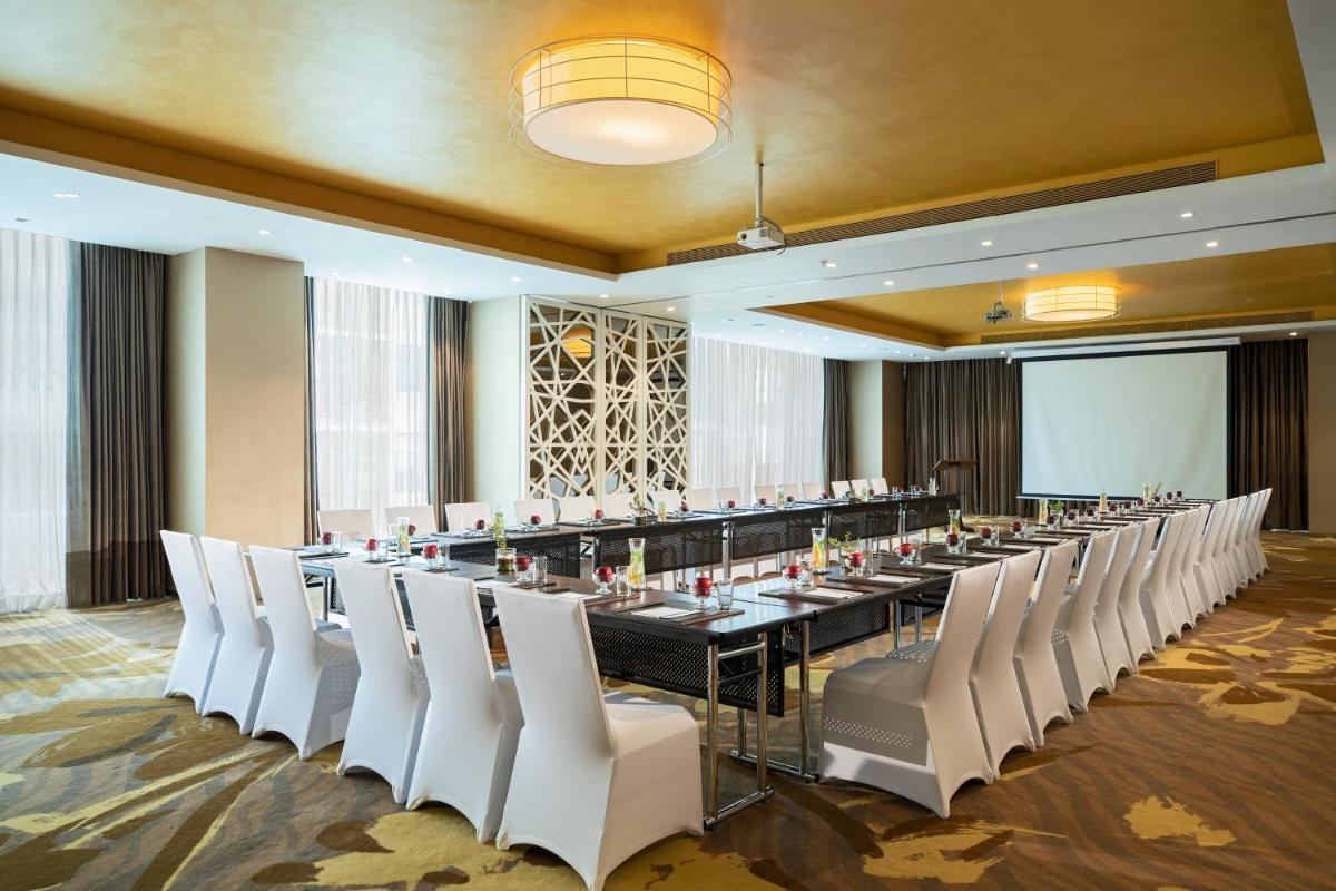 a large meeting room with a long table and white chairs at Renaissance Ahmedabad Hotel in Ahmedabad