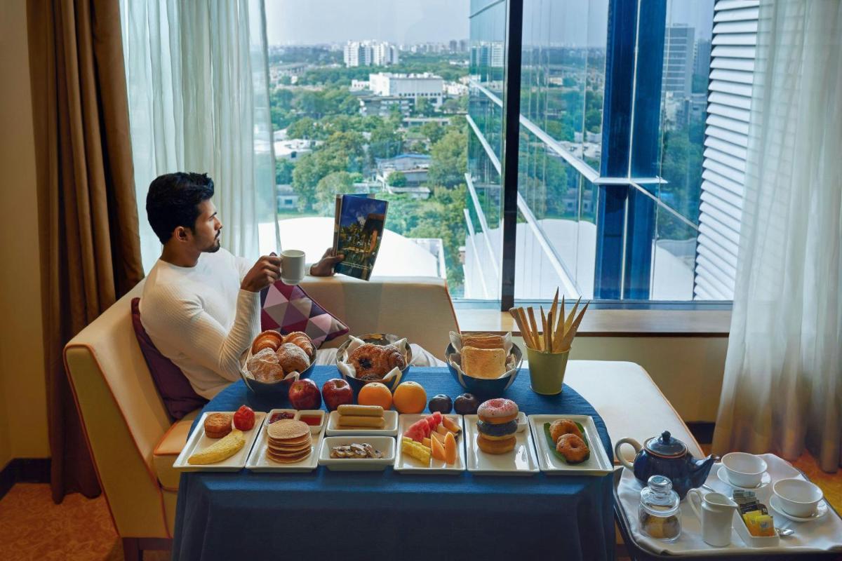a man sitting at a table with a tray of food at Renaissance Ahmedabad Hotel in Ahmedabad