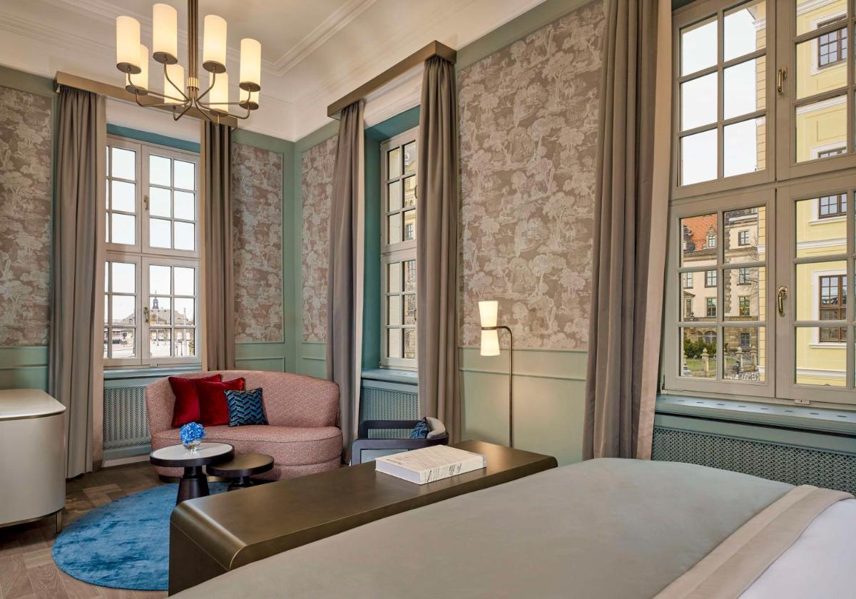 ein Schlafzimmer mit einem Bett und einem Stuhl und Fenstern in der Unterkunft Hotel Taschenbergpalais Kempinski in Dresden