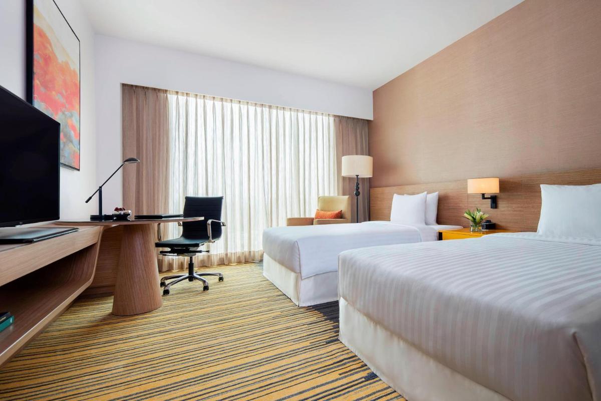 a hotel room with two beds and a desk and a television at Courtyard by Marriott Bengaluru Outer Ring Road in Bengaluru