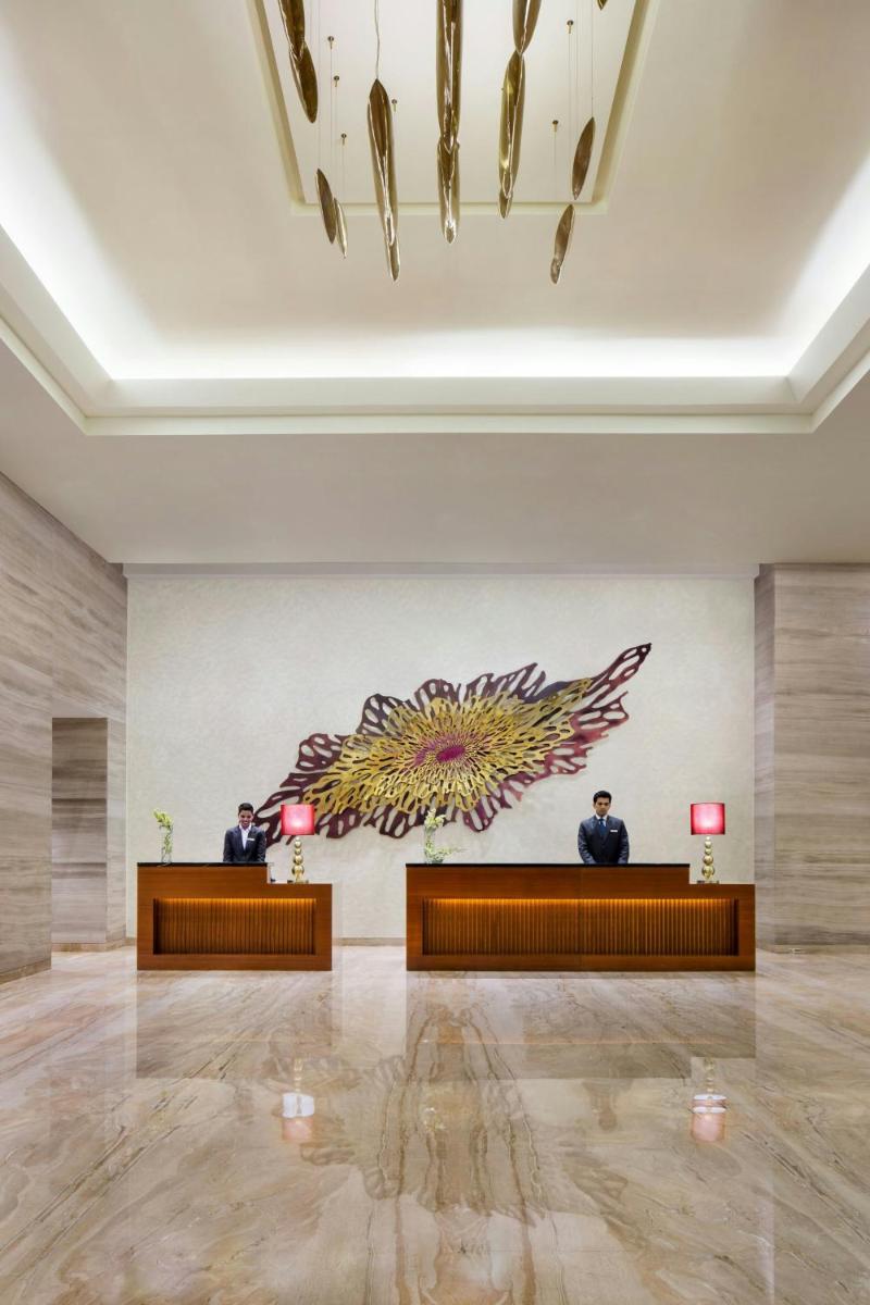 two men in a lobby with a painting on the wall at Courtyard by Marriott Bengaluru Outer Ring Road in Bengaluru