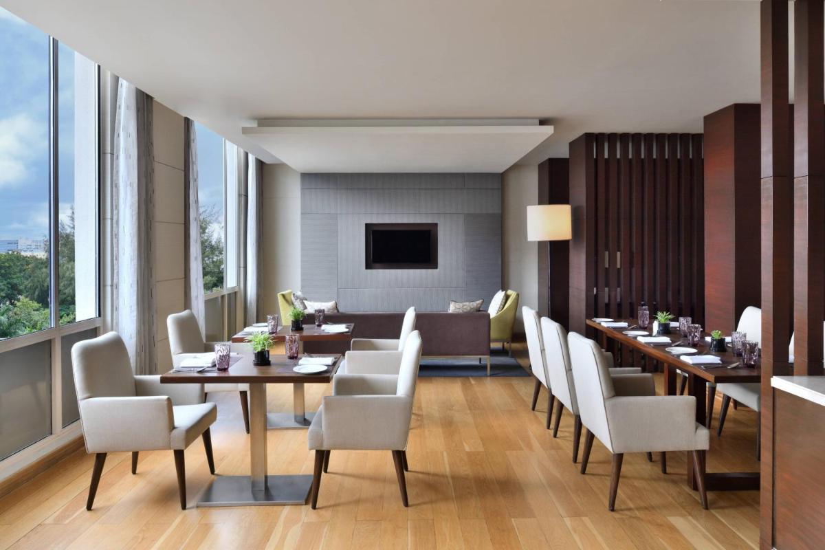 a dining room with tables and white chairs at Courtyard by Marriott Bengaluru Outer Ring Road in Bengaluru