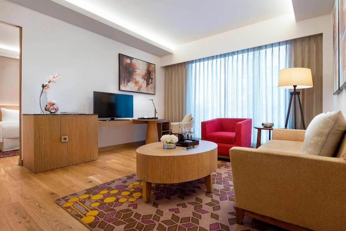 a living room with a couch and a table and a television at Courtyard by Marriott Bengaluru Outer Ring Road in Bengaluru