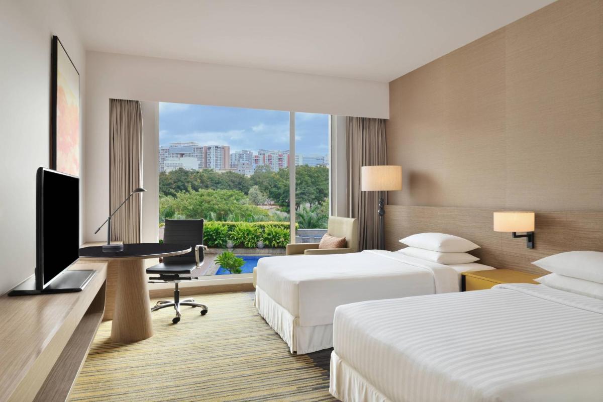 a hotel room with two beds and a flat screen tv at Courtyard by Marriott Bengaluru Outer Ring Road in Bengaluru a hotel room with two beds and a flat screen tv at Courtyard by Marriott Bengaluru Outer Ring Road in Bengaluru