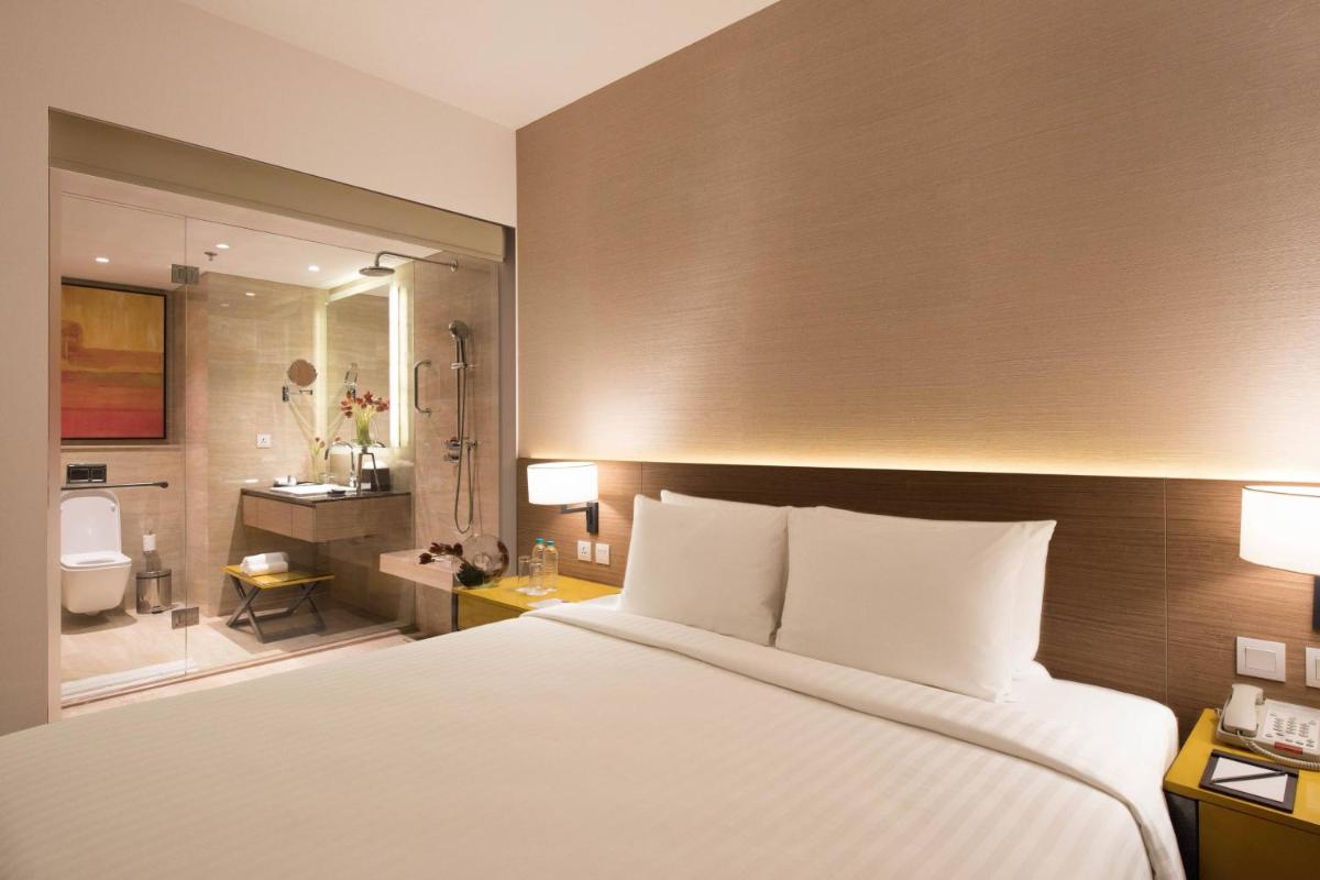 a bedroom with a large bed and a bathroom at Courtyard by Marriott Bengaluru Outer Ring Road in Bengaluru
