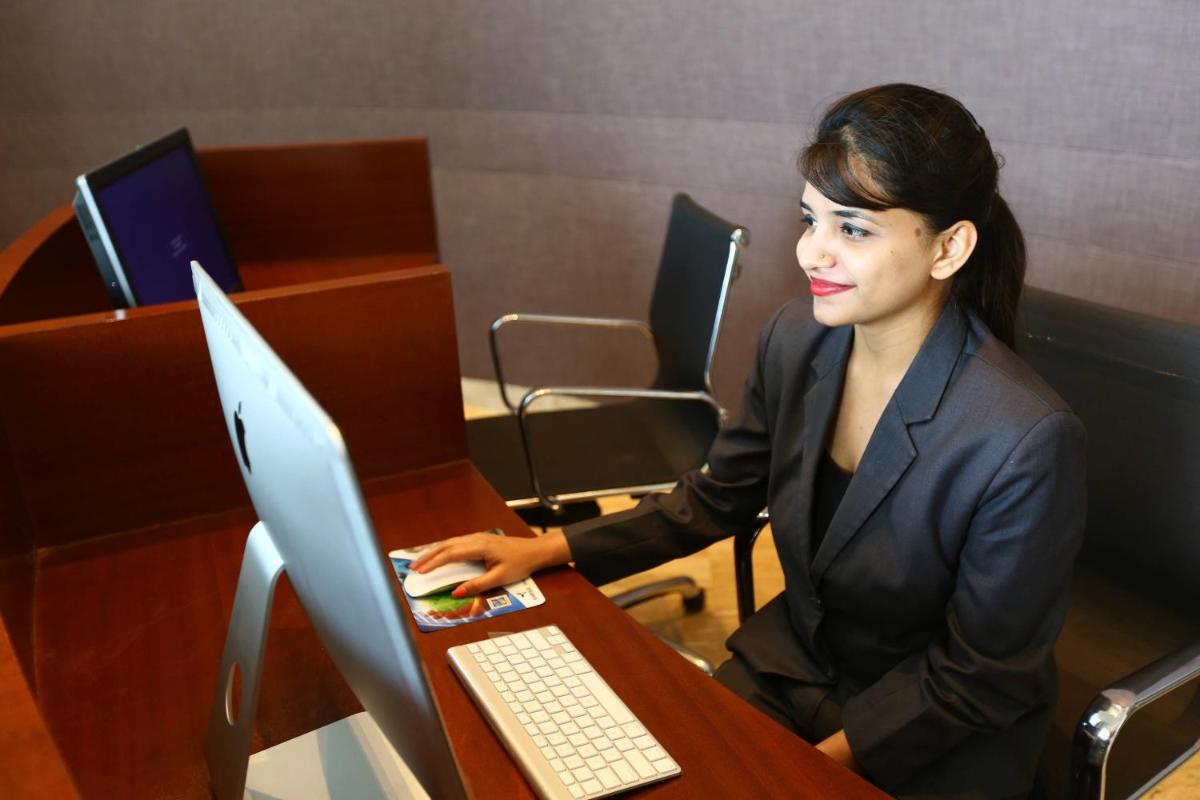 a woman sitting at a desk using a computer at Courtyard by Marriott Bengaluru Outer Ring Road in Bengaluru
