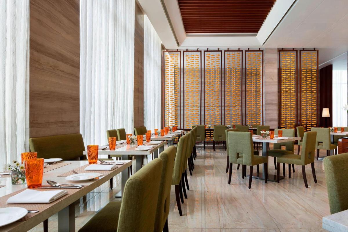a dining room with tables and chairs and windows at Courtyard by Marriott Bengaluru Outer Ring Road in Bengaluru