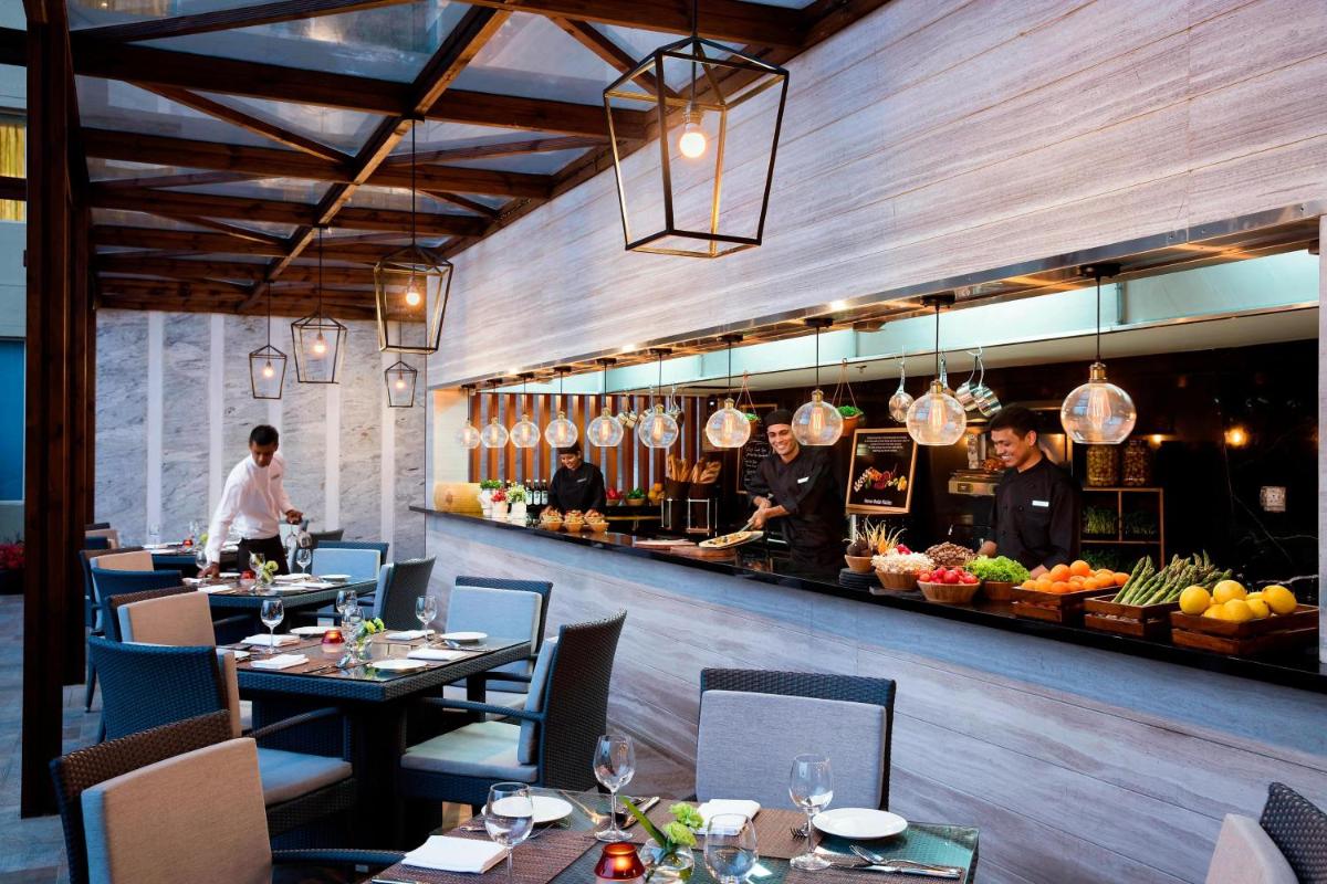 a restaurant with tables and a chef preparing food at Courtyard by Marriott Bengaluru Outer Ring Road in Bengaluru