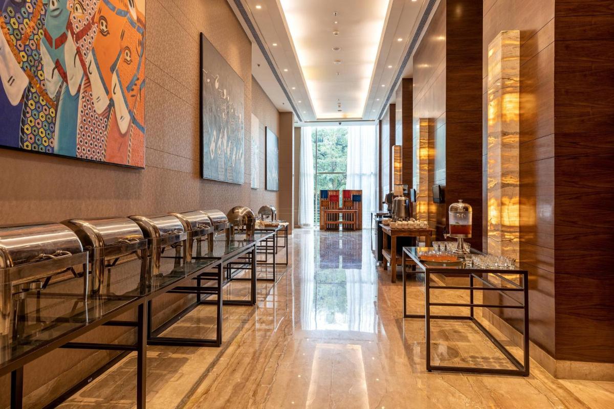 a lobby with a row of tables and chairs at Courtyard by Marriott Bengaluru Outer Ring Road in Bengaluru