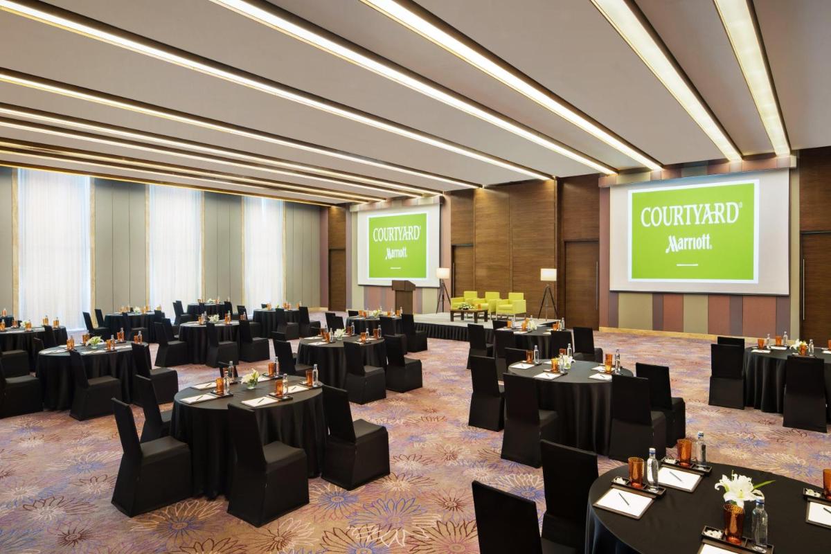 a conference room with black tables and chairs and a screen at Courtyard by Marriott Bengaluru Outer Ring Road in Bengaluru