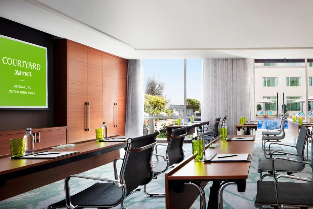 a conference room with tables and chairs and a screen at Courtyard by Marriott Bengaluru Outer Ring Road in Bengaluru +29 photos