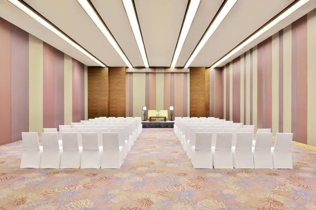 an empty room with white chairs and a podium at Courtyard by Marriott Bengaluru Outer Ring Road in Bengaluru
