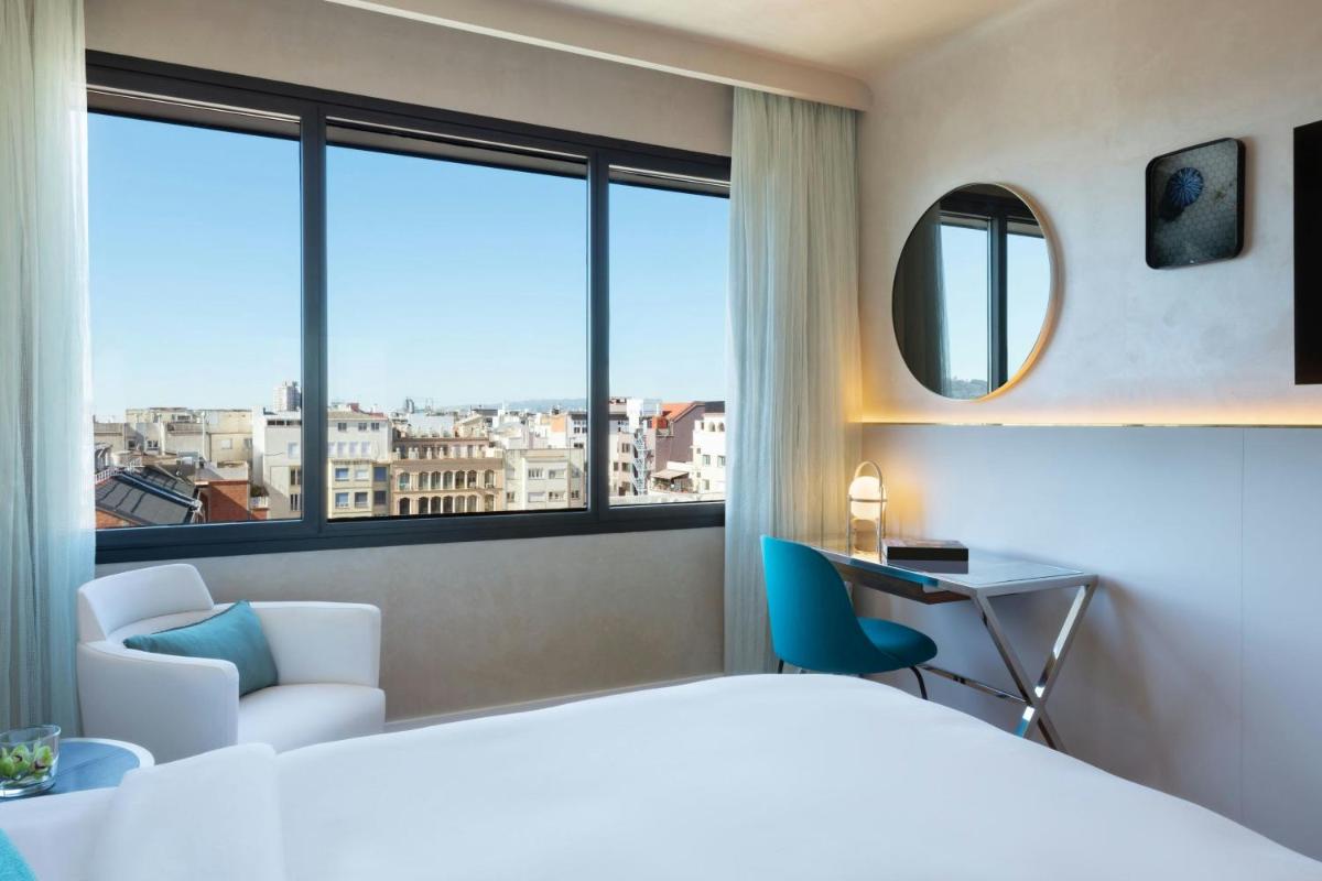 Una habitación de hotel con una cama, un escritorio y una ventana. en Renaissance Barcelona Hotel, en Barcelona