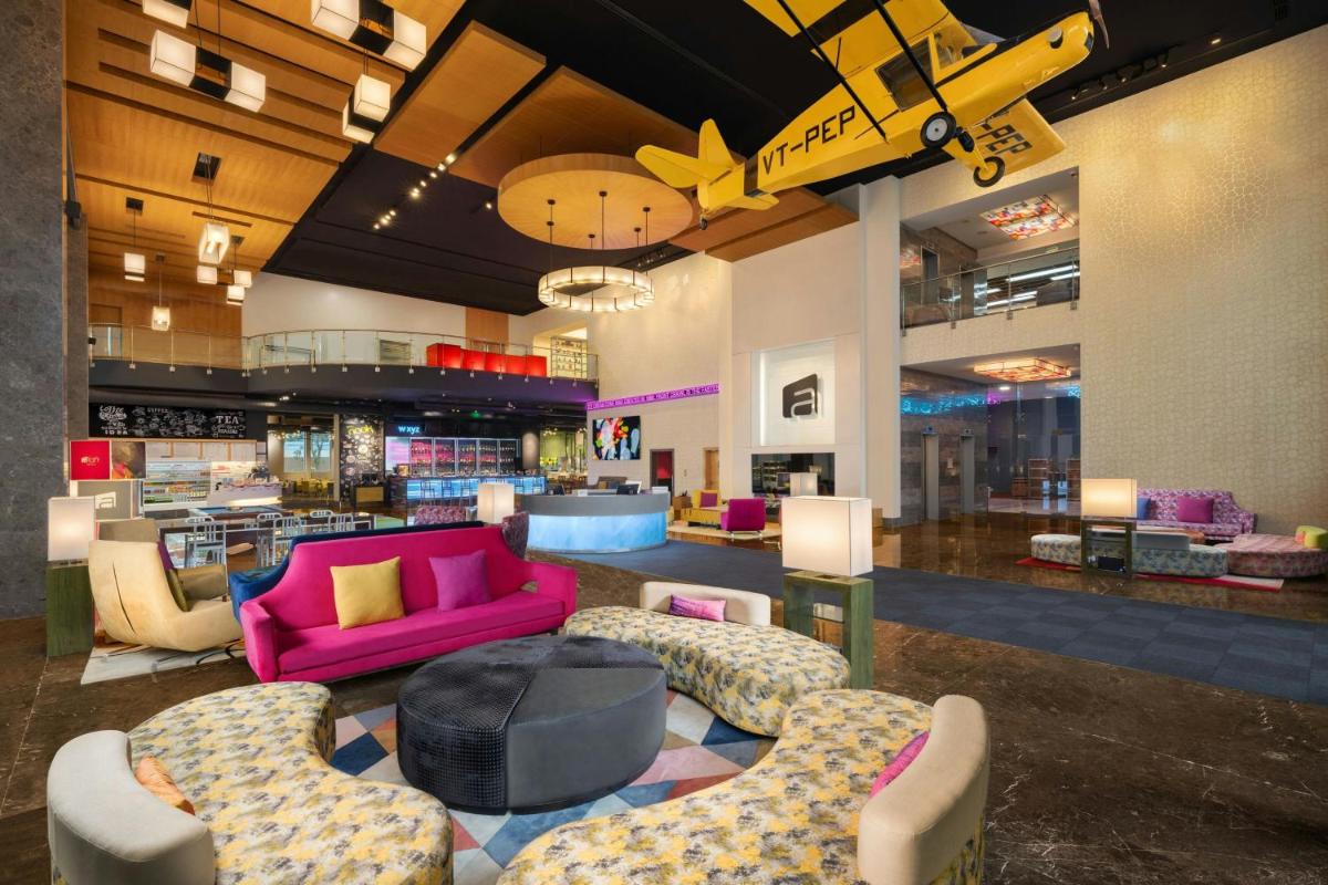 a large lobby with a pink couch and chairs at Aloft Bengaluru Outer Ring Road in Bengaluru