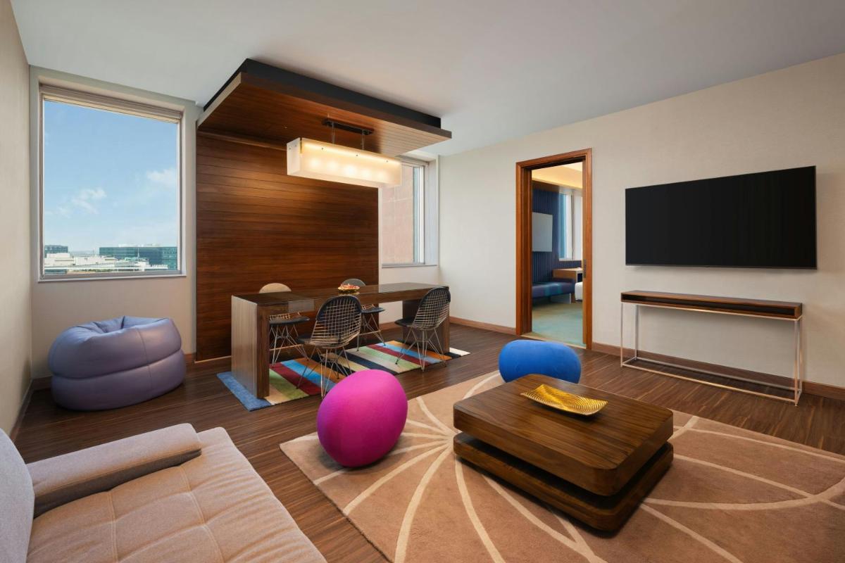 a living room with a television and a table and chairs at Aloft Bengaluru Outer Ring Road in Bengaluru