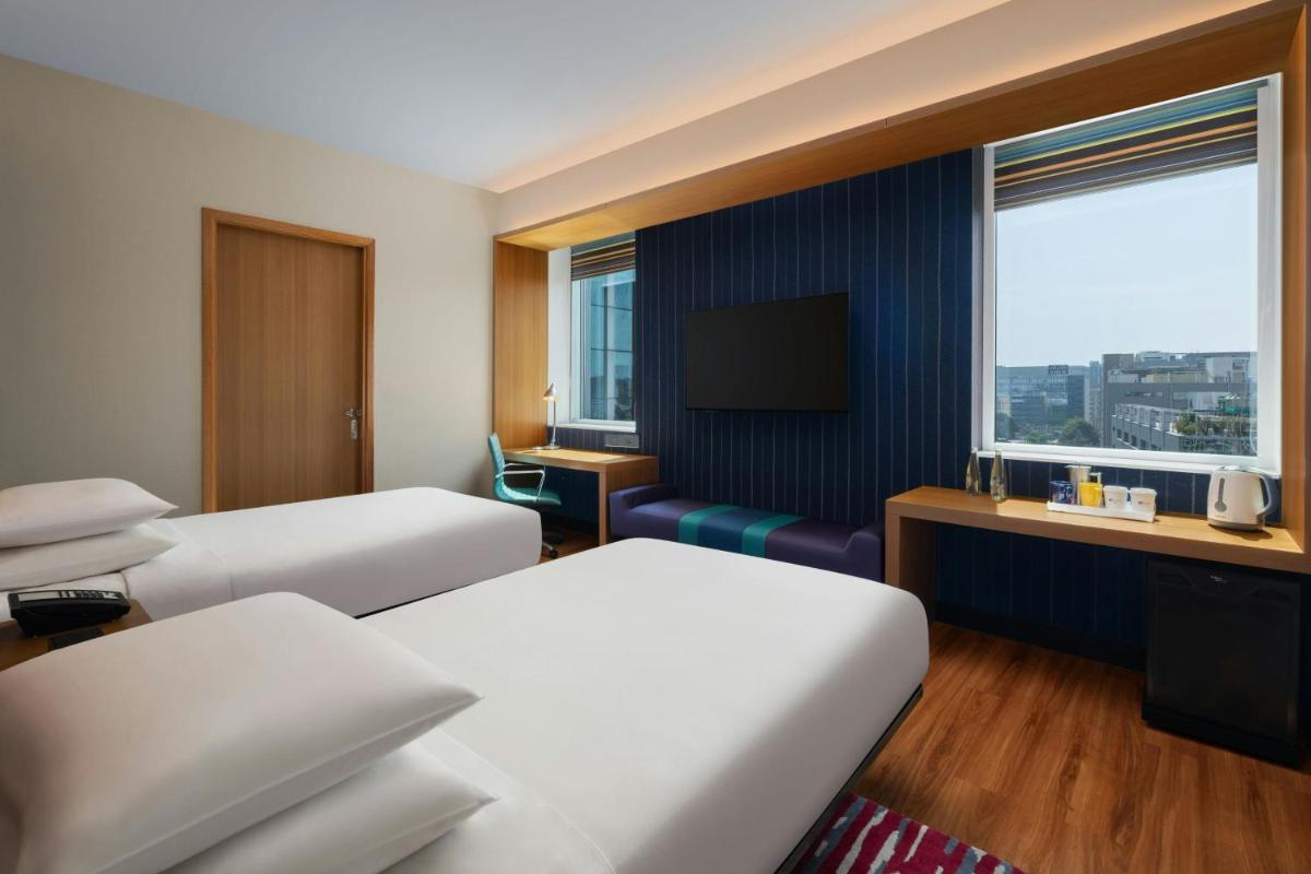 a hotel room with two beds and a television at Aloft Bengaluru Outer Ring Road in Bengaluru