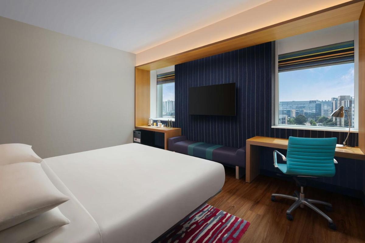a bedroom with a bed and a desk and a television at Aloft Bengaluru Outer Ring Road in Bengaluru