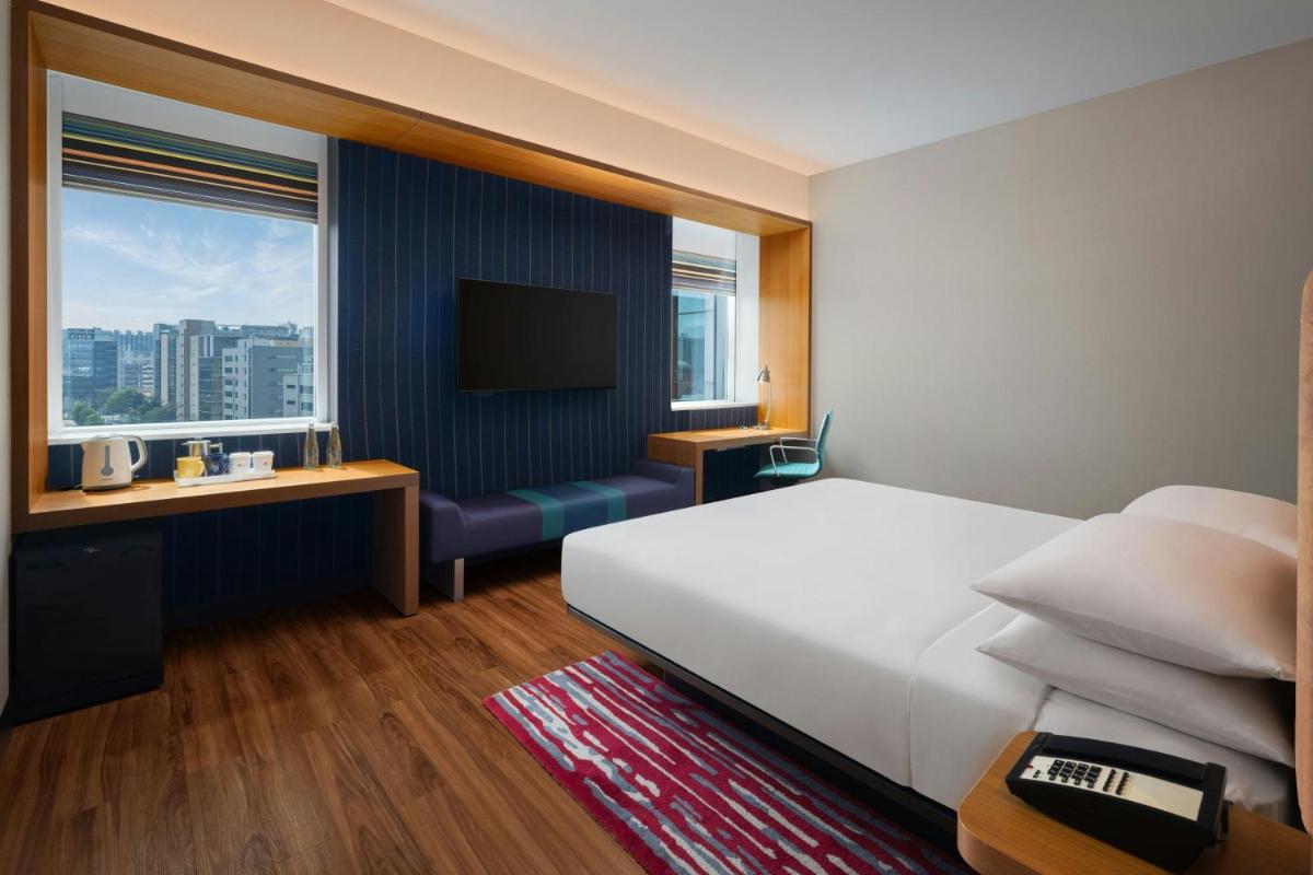 a hotel room with a bed and a television at Aloft Bengaluru Outer Ring Road in Bengaluru