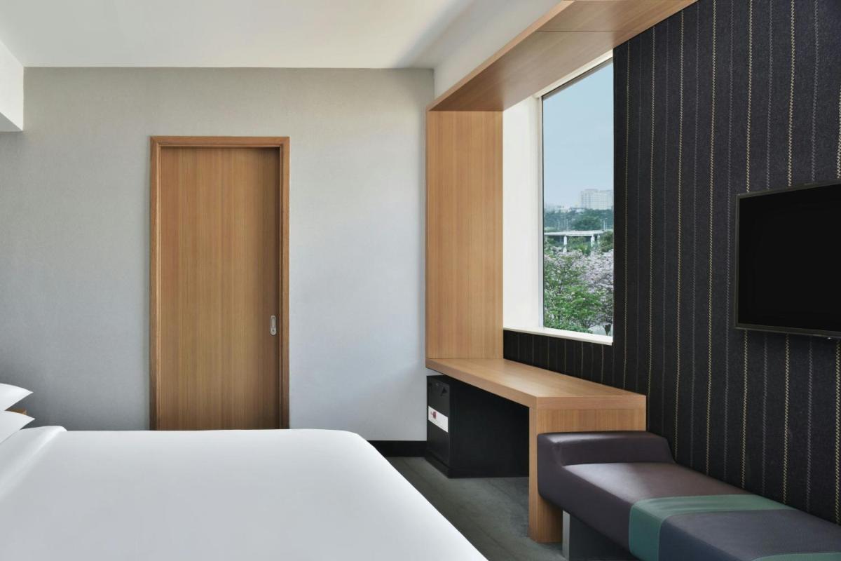 a hotel room with a bed and a television at Aloft Bengaluru Outer Ring Road in Bengaluru