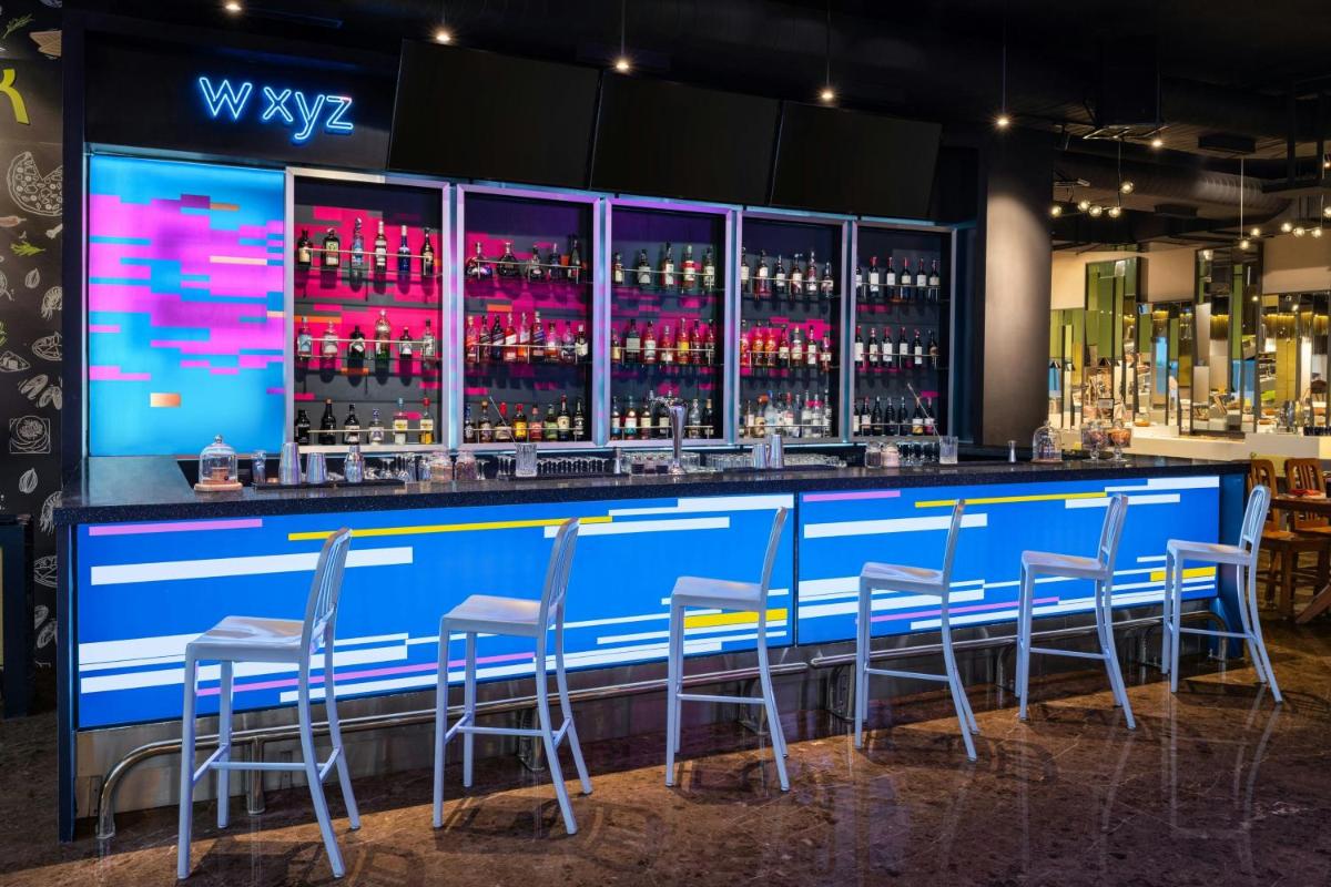 a bar with chairs and bottles of wine at Aloft Bengaluru Outer Ring Road in Bengaluru