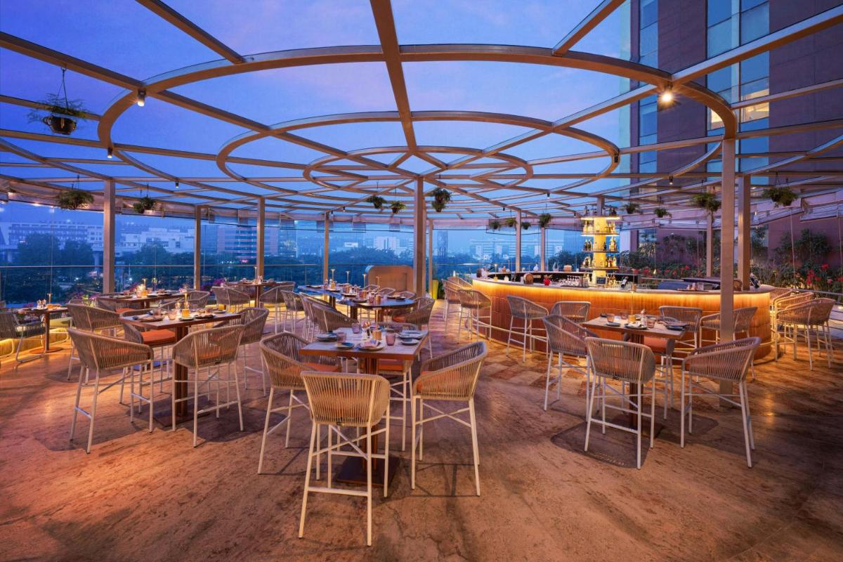a restaurant with tables and chairs in a building at Aloft Bengaluru Outer Ring Road in Bengaluru