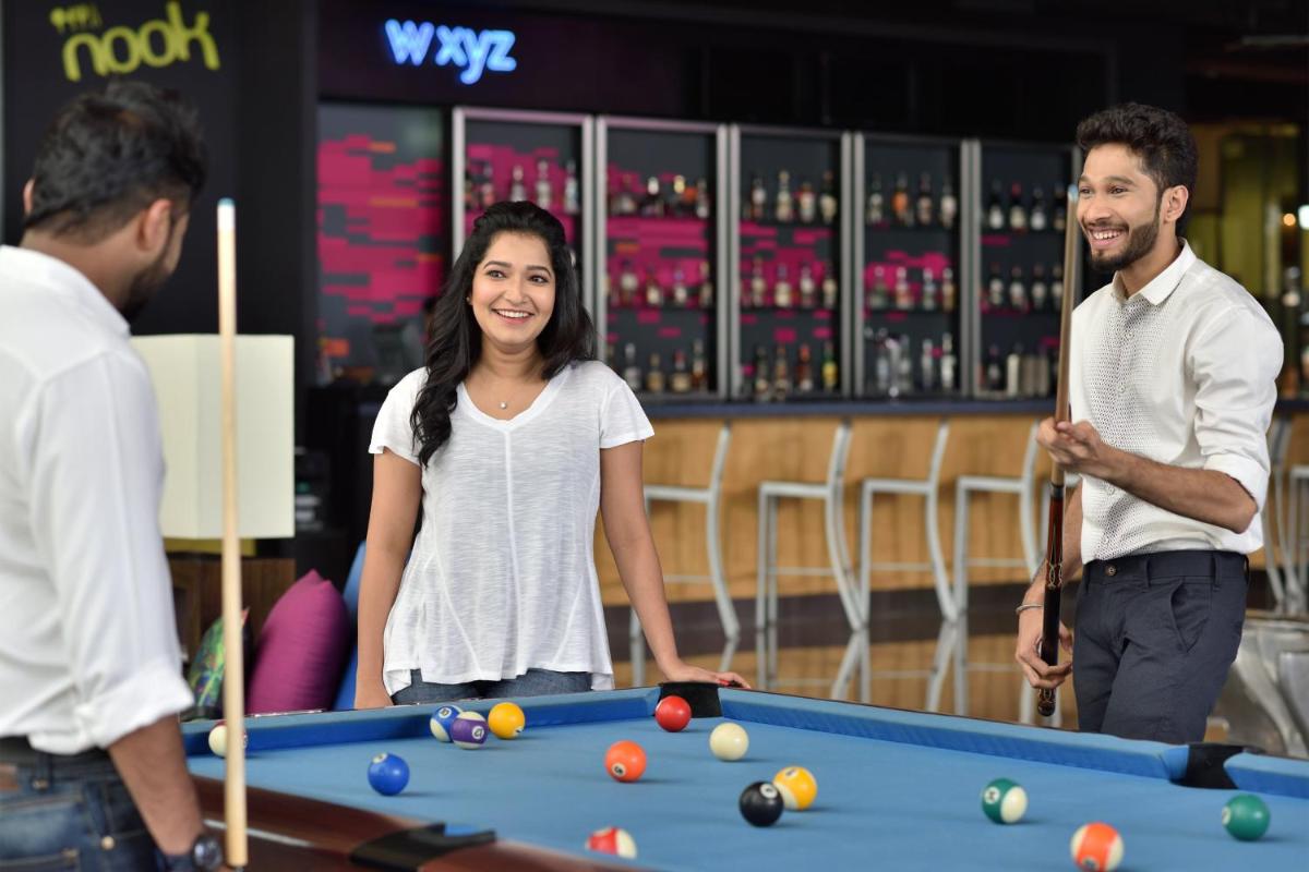 a woman and two men standing around a pool table at Aloft Bengaluru Outer Ring Road in Bengaluru